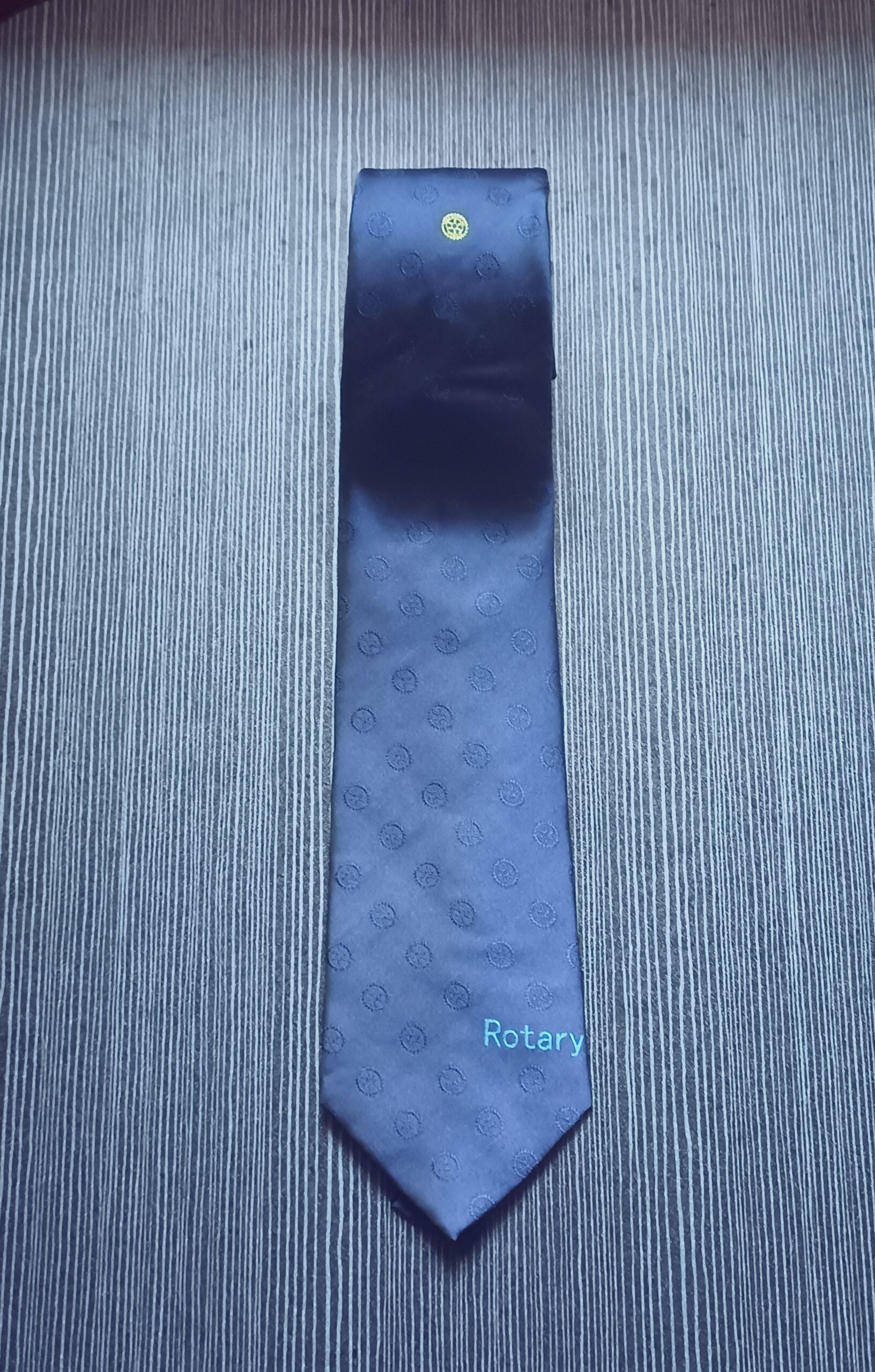 Cravatta blu in poliestere con logo e scritta Rotary ricamati su sfondo con loghi in trasparenza